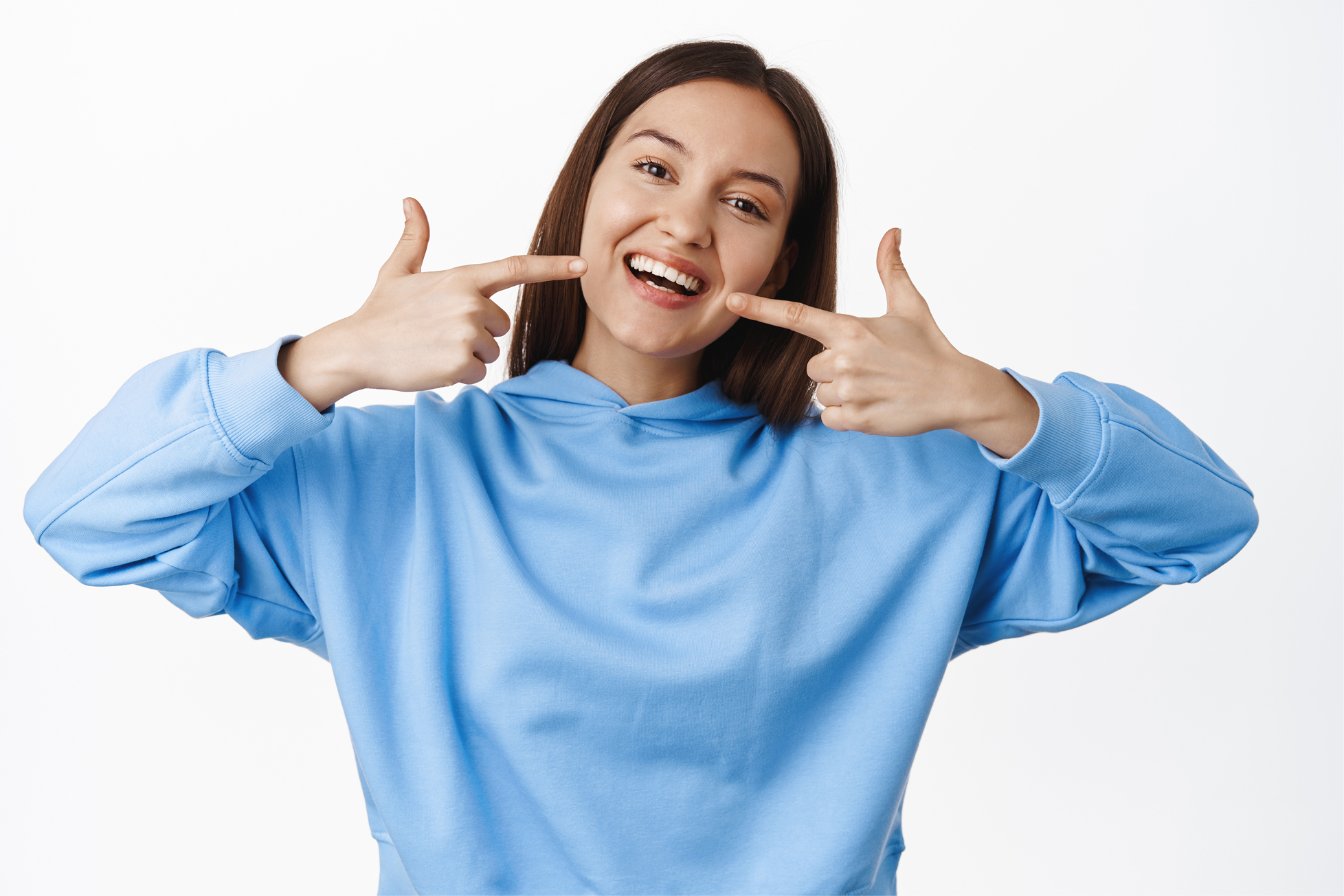 happy-girl-pointing-fingers-white-perfect-smile-straight-whitened-teeth-standing-hoodie-against-white-background